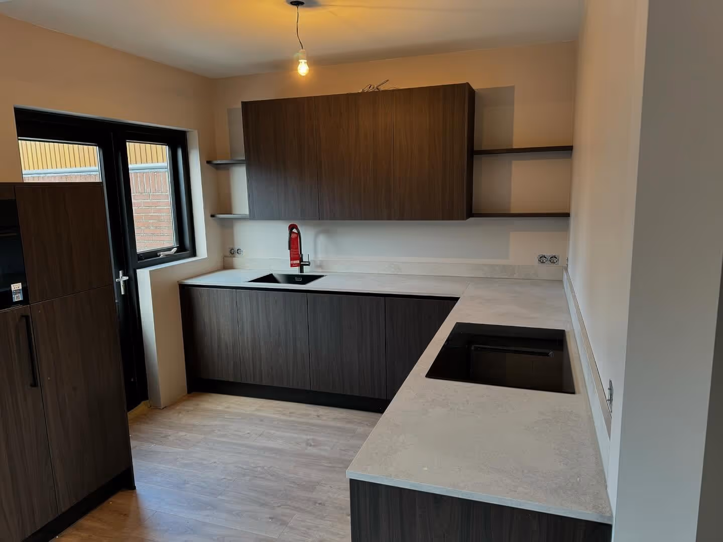 A modern bedroom with a black bed, two framed line art prints, and a plant on a nightstand.