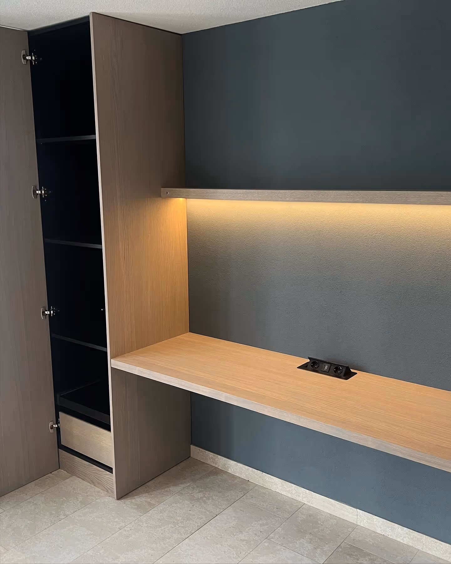  A brightly lit corner of a room features a modern white armchair with light wood accents, a small white coffee table with a plant, and a clear vase with white branches next to a sunlit window.